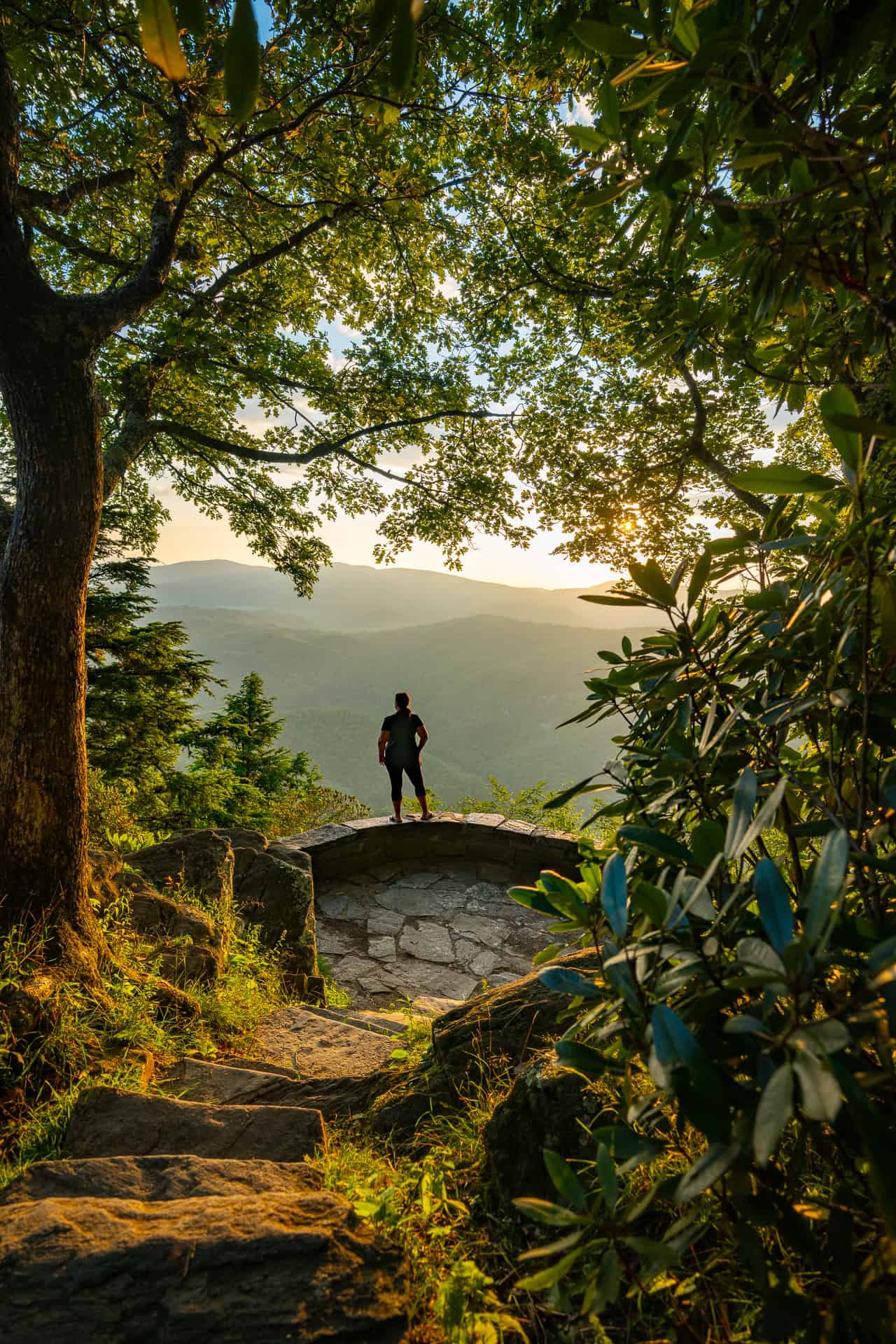 Sarah's silhouette overlooking the mountains with the sun rising behind