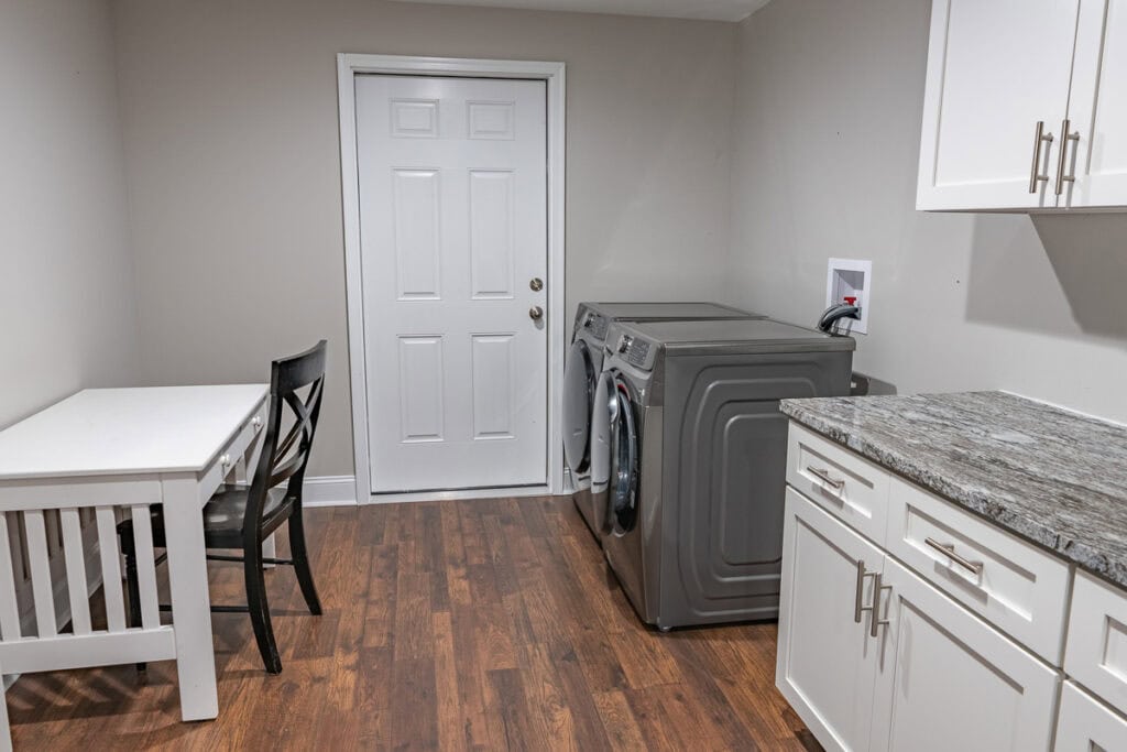 Bright and functional laundry room with modern appliances, white cabinetry, and a small workspace.