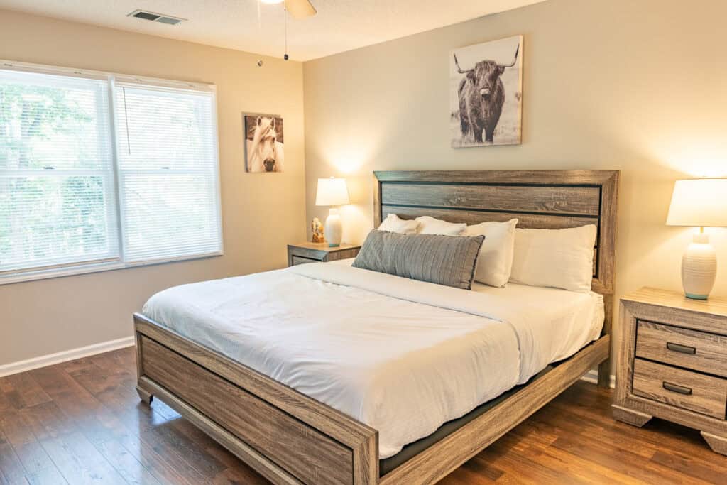 Second bedroom with a king-size bed, warm-toned decor, and large windows overlooking the outdoor scenery.