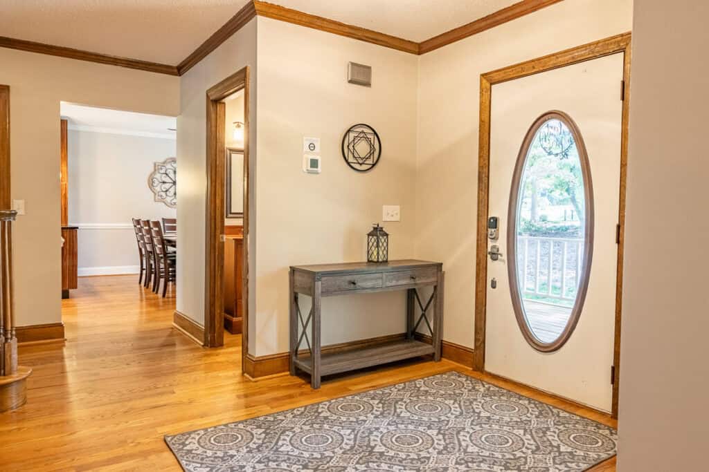 An inviting entryway featuring an oval glass-paneled door, a decorative console table, and hardwood floors.