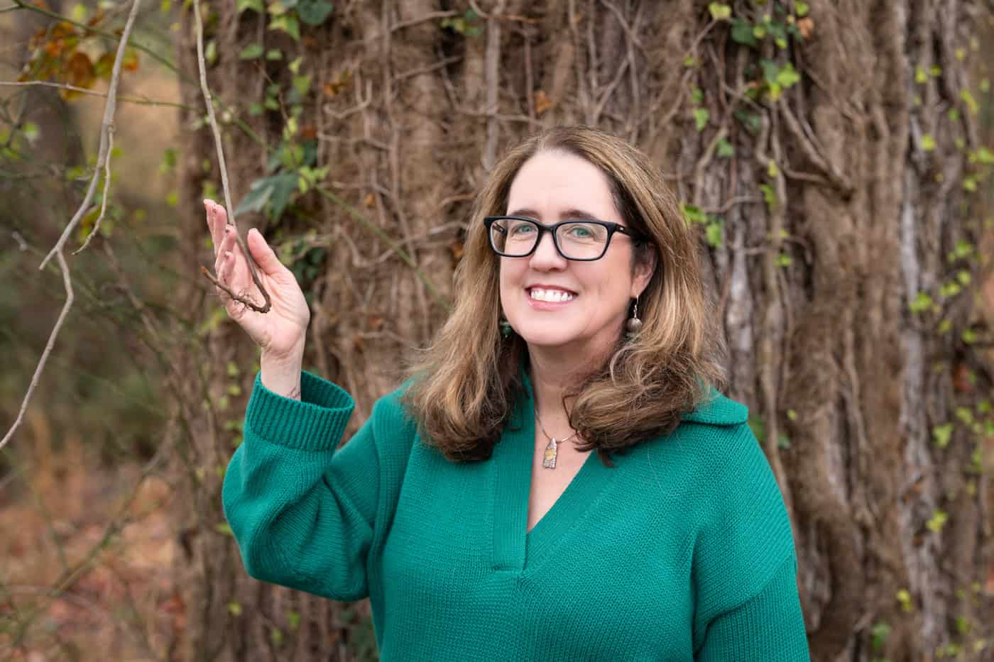 a woman smiling in front of a tree