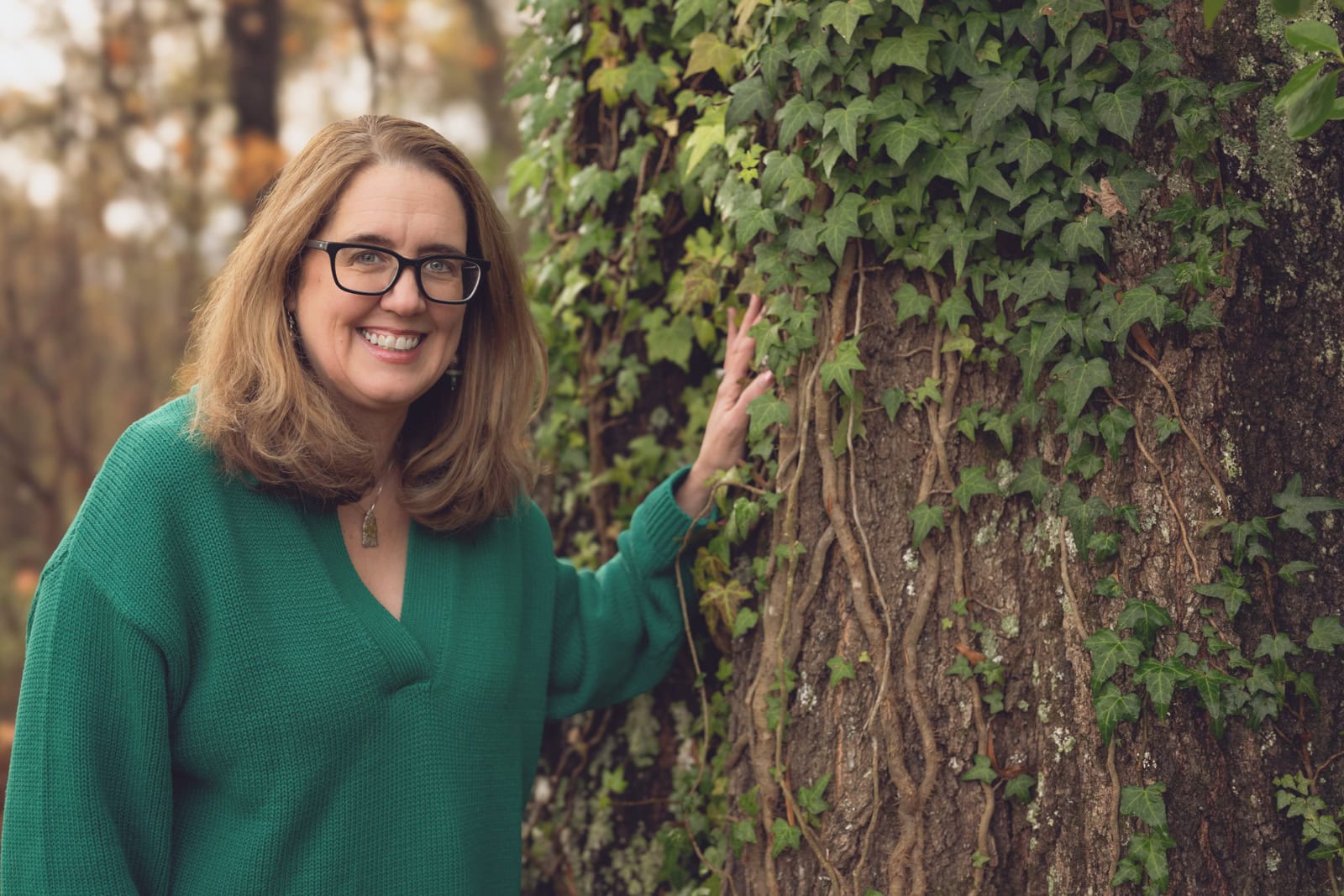 a woman smiling next to a tree