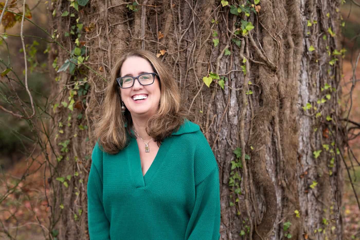 a woman smiling in front of a tree