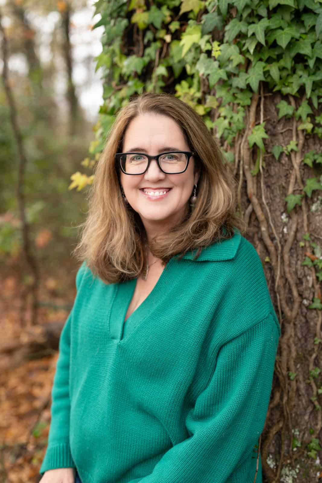 a woman in a green shirt and glasses smiling