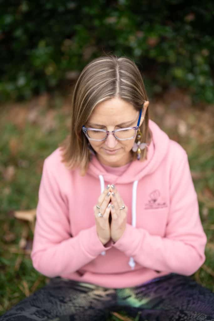 a woman in a pink hoodie with her hands together