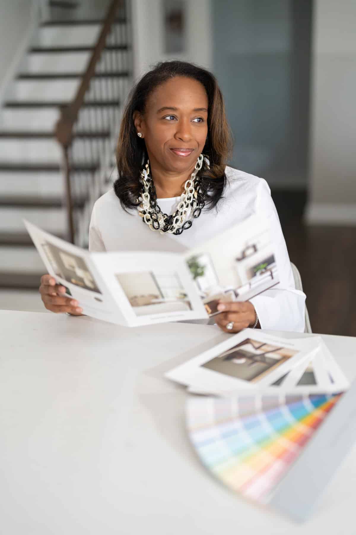 a woman sitting at a table looking at a catalog