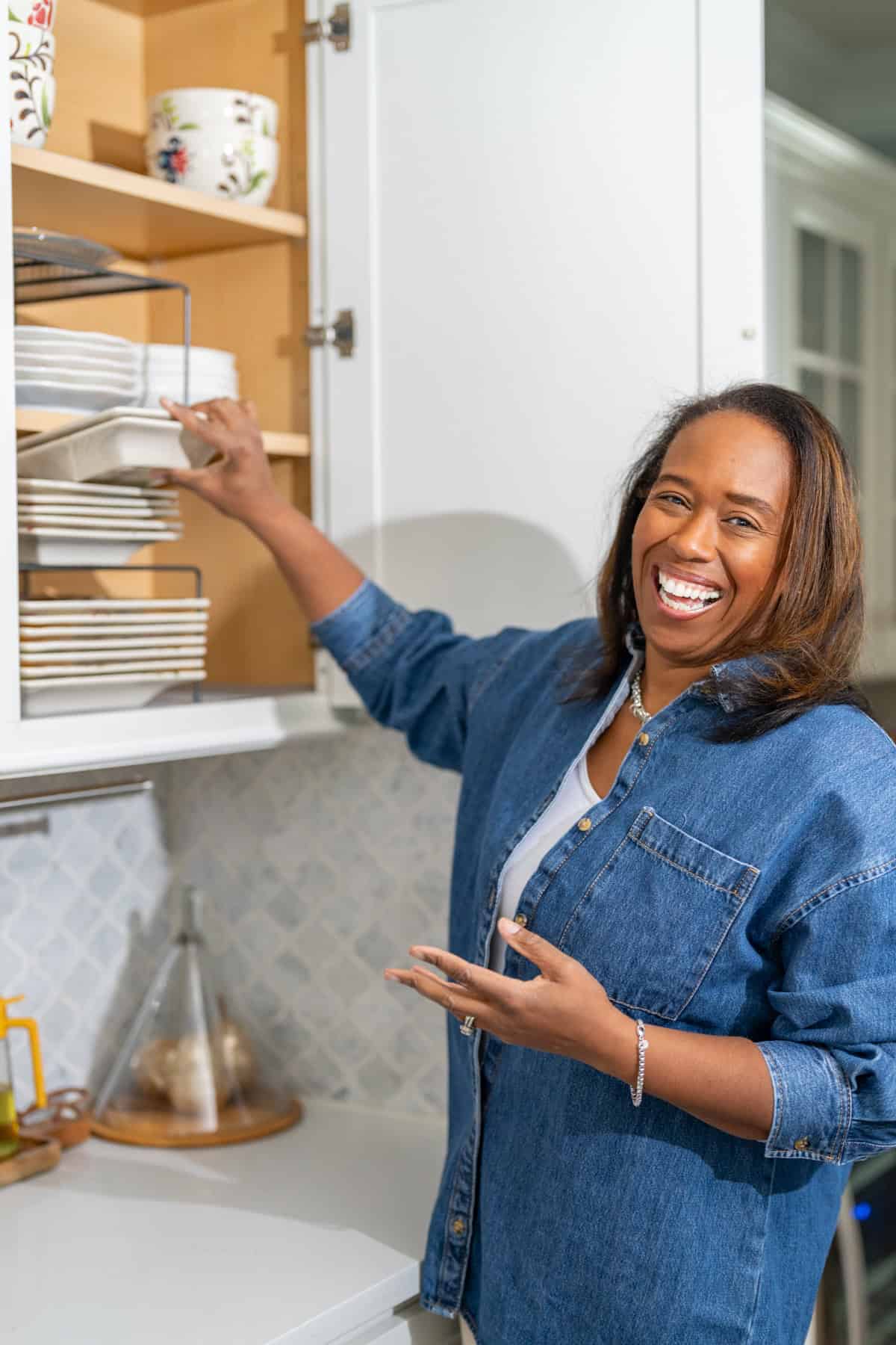 a woman smiling and putting plates in a cabinet