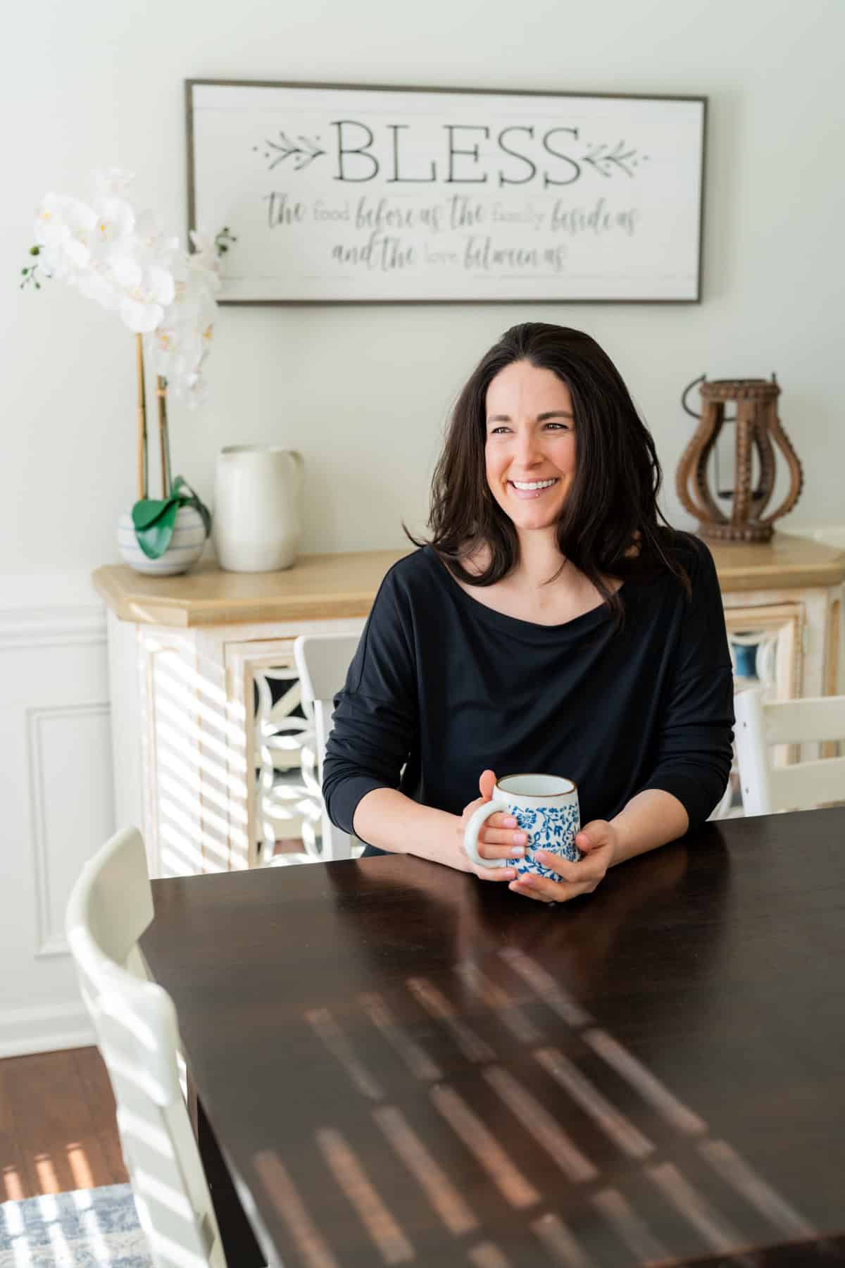 a woman sitting at a table holding a mug