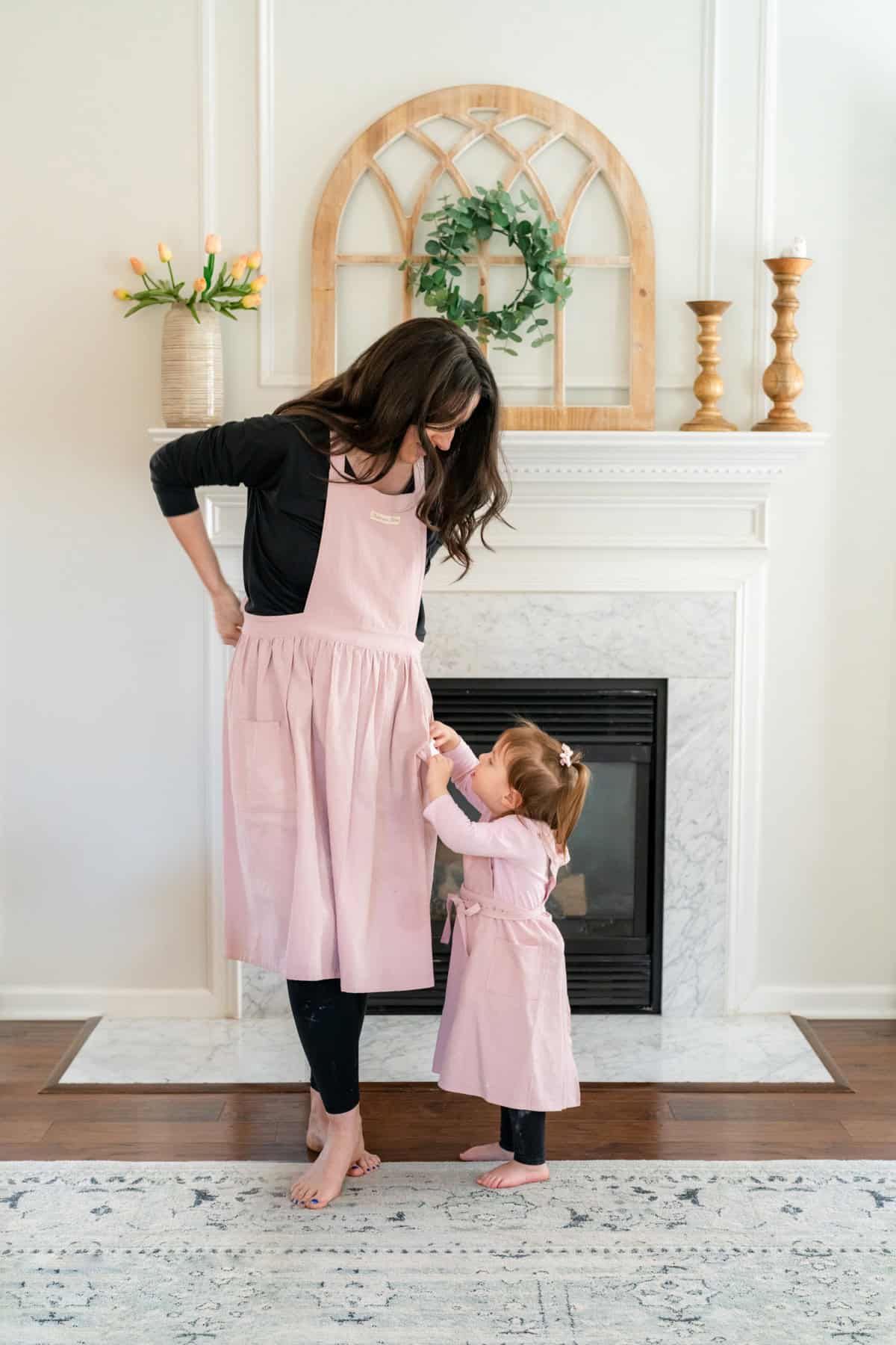 a woman and a child standing in front of a fireplace